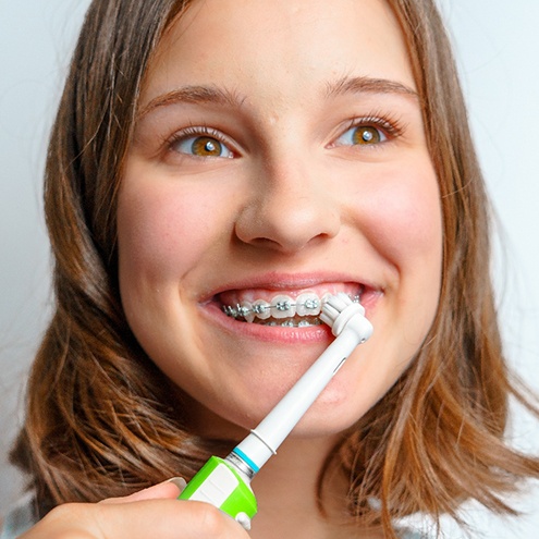 a woman with braces brushing her teeth