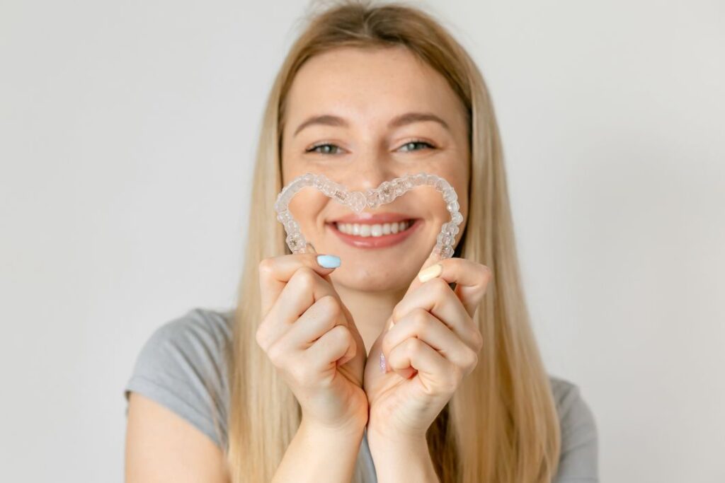 A woman making a heart with her clear aligners