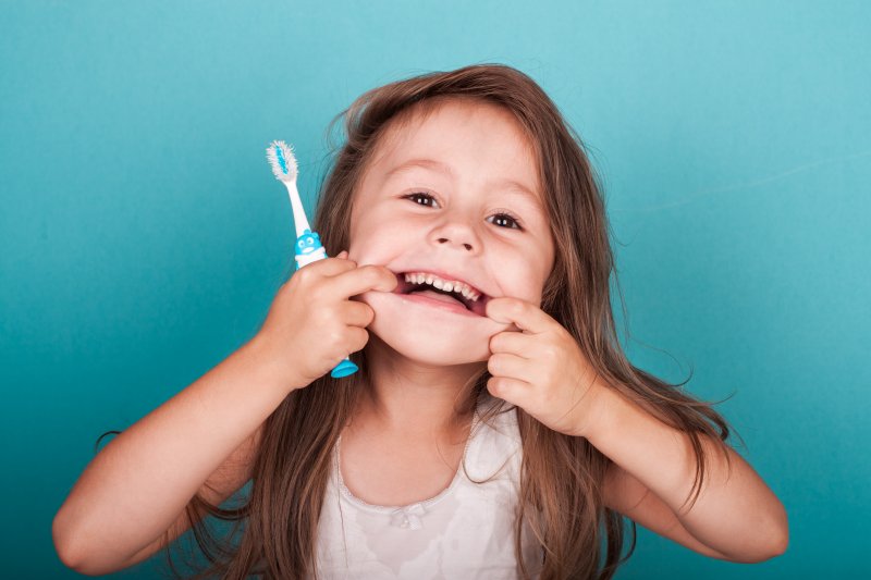 Kid makes silly face with toothbrush